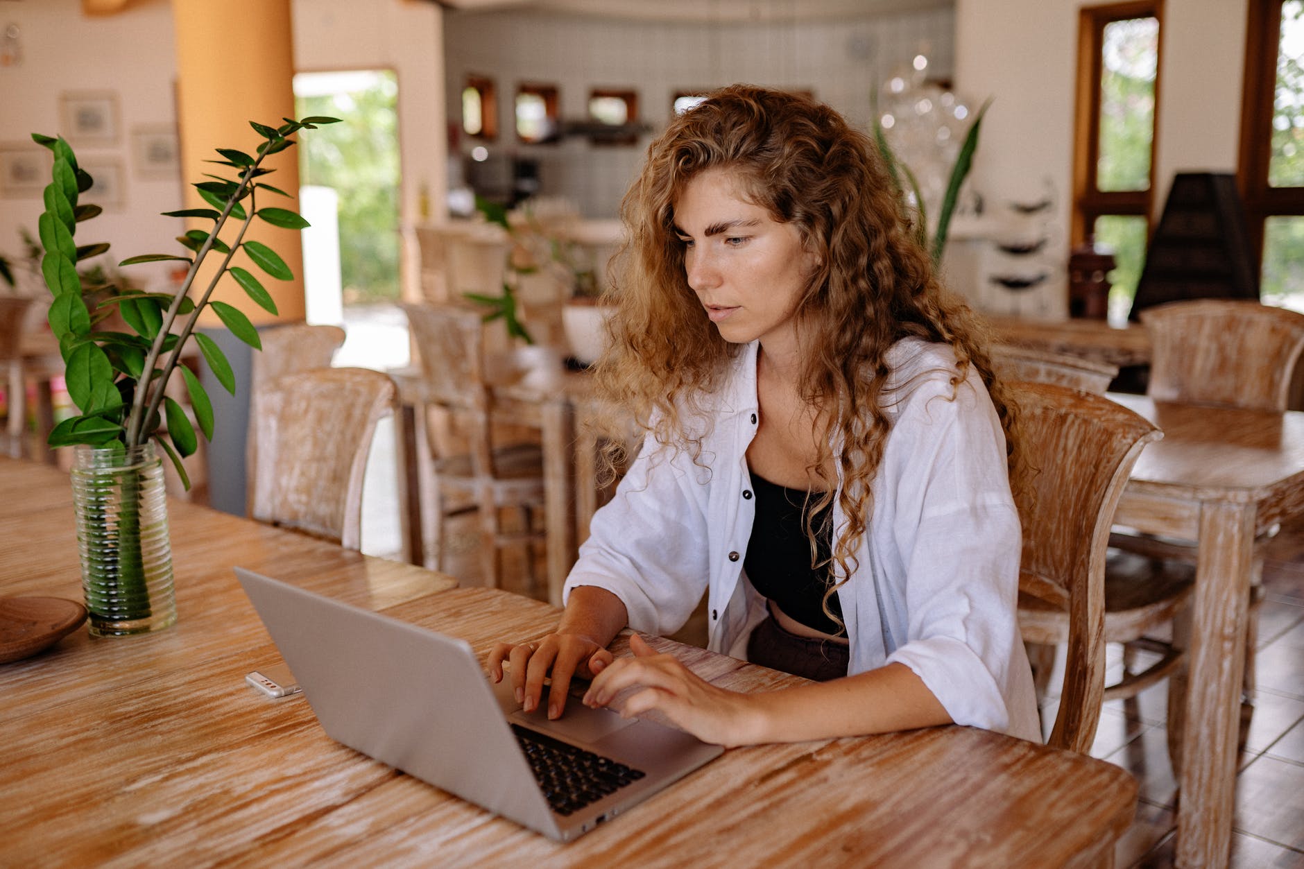 young woman using laptop at vintage cafe, woman working on her laptop